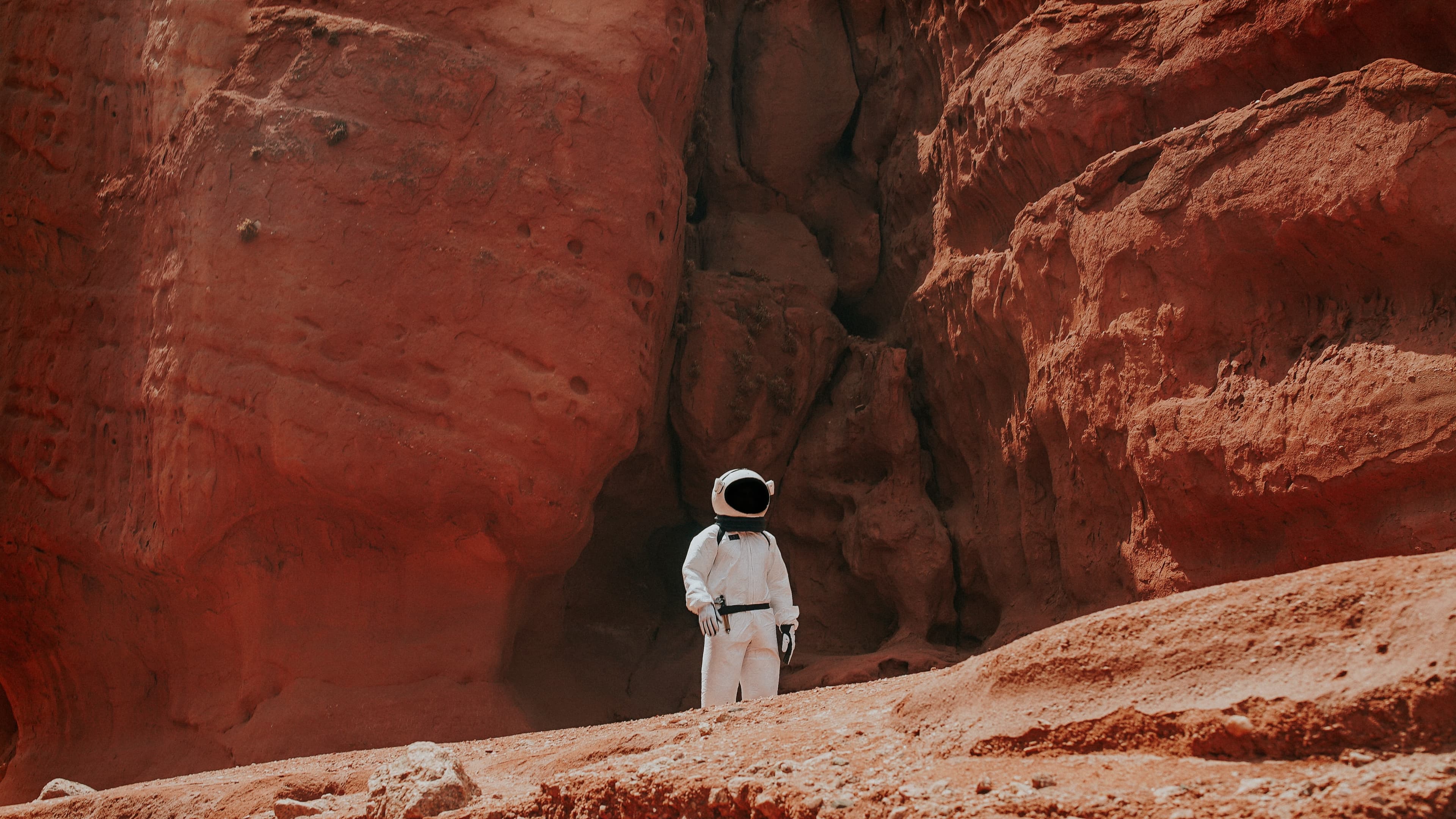 Astronaut exploring a red, Mars-like canyon